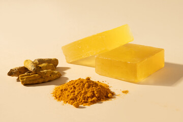 Handmade turmeric soap bars, powder and turmeric root on yellow background. Organic skincare product perfect for wellness, beauty, and organic body care concepts. Vertical. Close up.
