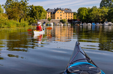 Kayaking through the calm waters of Långholmen in central Stockholm, with boats, trees, and...