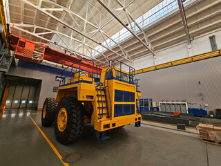 A yellow and blue truck is parked in a large building. The truck is parked in a large open space...