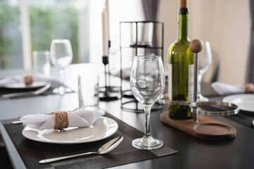 Elegant Dining Table Setting with Wine Bottle and Glassware in Modern Interior, Ideal for Celebrations and Special Occasions