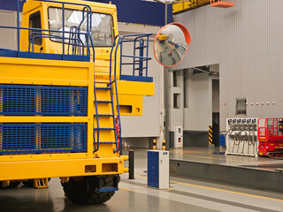 A large yellow and blue truck. The truck is parked in a large industrial building