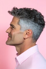 Fototapeta premium Idea depiction of style for aging men. Pink solid background. A strong and confident man with an engaging smile. Modish men's slicked back haircut - midlife middle eastern man with curly hai.