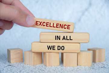 Hand pushing wooden blocks spelling EXCELLENCE with emphasis on value driven leadership and top...