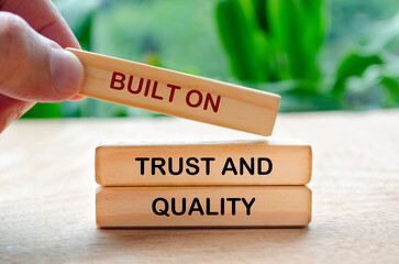 Hand placing wooden block that says Built On Trust And Quality text on Quality