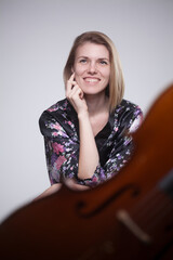 Woman in floral robe smiling, with cello in foreground. © HD92
