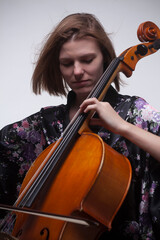 Woman playing cello, wearing floral kimono, close-up. © HD92