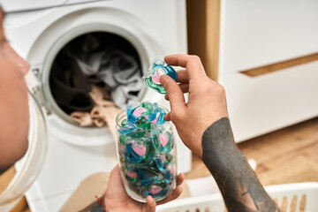 Handsome tattooed man doing laundry while enjoying a cozy day at home