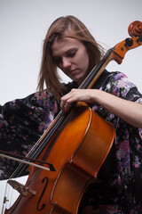 Woman playing cello, wearing floral kimono, studio shot.