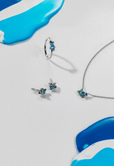 A silver ring, earrings, and a necklace with turquoise accents are artistically arranged on a light...