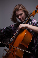 Woman playing cello, wearing floral kimono, studio shot.