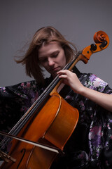 Woman playing cello, wearing floral kimono, studio shot.