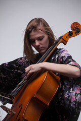 Woman playing cello, wearing floral robe, studio shot.