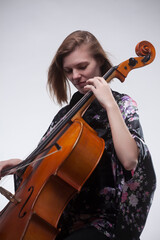 Woman playing cello, wearing floral kimono, studio shot.
