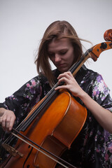 Woman playing cello, close-up, wearing floral robe, white background.