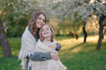Fototapeta premium A mother hugs her child in the park. A woman and a teenage girl. A happy family, mom and daughter, playing in nature.