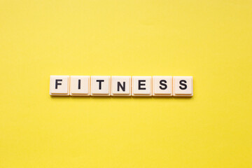 Fitness word with alphabet cubes isolated on yellow background
