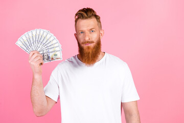 Fashionable bearded man holding fan of dollars against pink background symbolizing wealth and...
