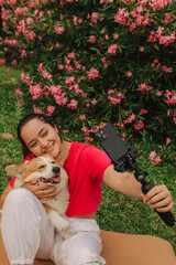 Young girl with Corgi recording video on phone share via app her travel vacation. Gen Z influencer...