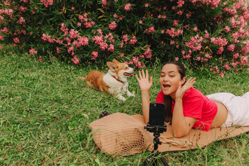 Young girl with Corgi recording video on phone share via app her travel vacation. Gen Z influencer shooting social media stories. Concept of friendship between a dog and human. Part of a series. UGC