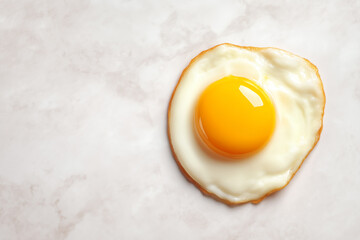 Cracked egg with bright yolk rests on polished marble surface, casting rich shadows. Clean background offers space for overlay text. Concept of culinary arts, gourmet cooking, food photography