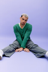 Stylish young man showcases unique fashion against a vibrant purple background