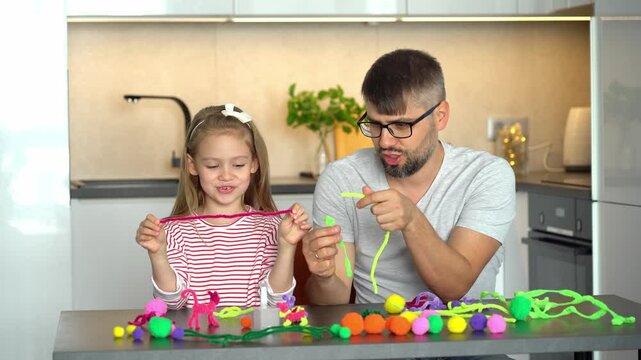 Father and little daughter make diy from colored chenille wire toys. Happy family create handmade craft. Leisure with children. Education