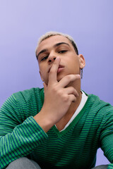 Stylish young man showcases unique fashion choices against a vibrant purple background