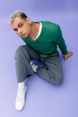 Stylish young man in a vibrant outfit posing against a captivating purple backdrop