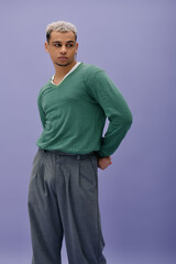 Young african american man showcases unique fashion style against purple backdrop
