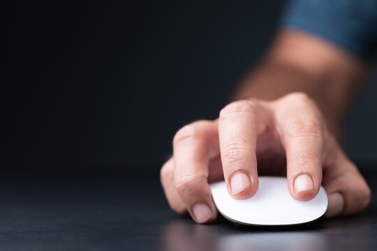 Close-up of a hand clicking a white wireless mouse on a dark background