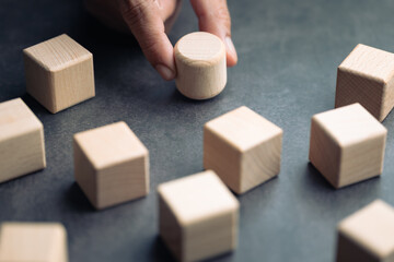 A hand picks a round block among cubes, symbolizing standout ideas, brand differentiation,...