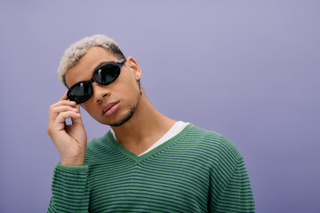 Young man showcases urban style with dyed hair against a vibrant purple backdrop