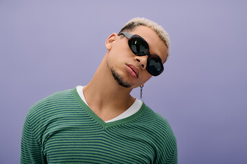 Stylish young man with dyed hair poses confidently on vibrant purple background