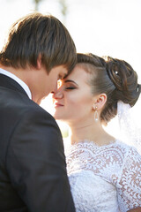 A bride and groom are embracing each other, with the bride wearing a white dress