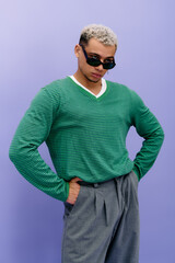 Stylish young man showcases modern fashion against a vibrant purple backdrop