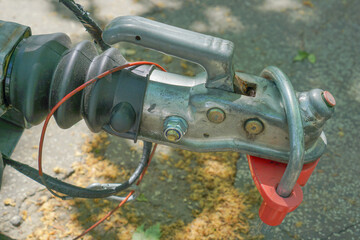 Detailed view of a metal trailer hitch with red security lock and cables, showing mechanical parts...