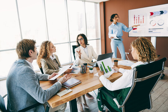 Group of diverse business professionals collaborating on a teamwork project in a modern office space with a presentation.