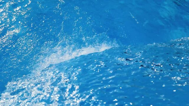 Video footage of blue clear water falling into a blue pool.