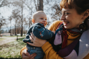 A happy mother enjoys time with her baby in a sunlit park, showcasing love and joy in this outdoor...