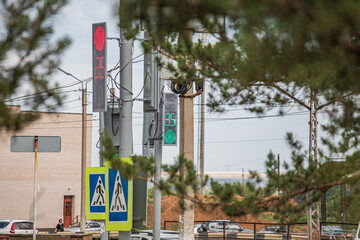 City traffic lights and road signs at a crossroads among the trees. Soft focus