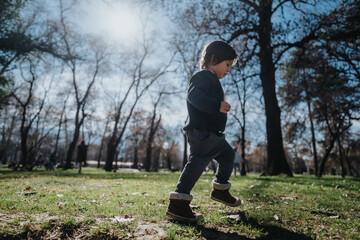A child strolling through a vibrant park filled with sunlight and shadows from trees, capturing the...