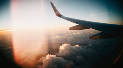 Airplane flying low over foggy mountains, view from plane window of plane wing and sky sunrise