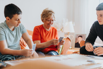 Grandmother playing cards with grandchildren at home. Warm familial connection and shared activity...