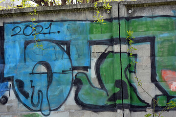 Unusual wall graffiti along the entire concrete fence in the form of unusual inscriptions of the Ukrainian style. They are painted with a can of blue, green and orange.