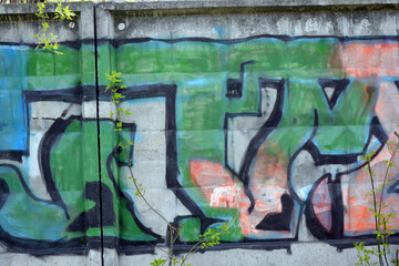 Unusual wall graffiti along the entire concrete fence in the form of unusual inscriptions of the Ukrainian style. They are painted with a can of blue, green and orange.