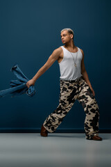 Young man showcases vibrant fashion with denim amid a striking blue backdrop