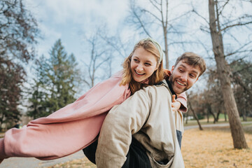 A joyful couple laughing and embracing outdoors, with colorful autumn scenery in the background,...
