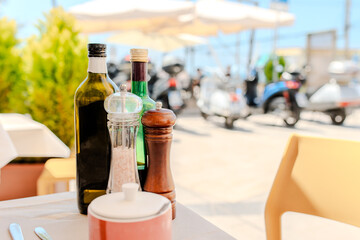 Similar scene with olive oil, salt, and pepper on a terrace table in Italy, different angle.