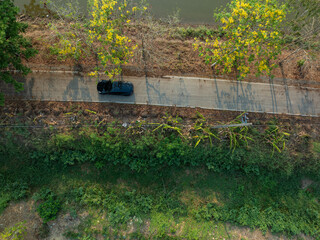 Aerial view Ev car drive on rural road tropical tree forest