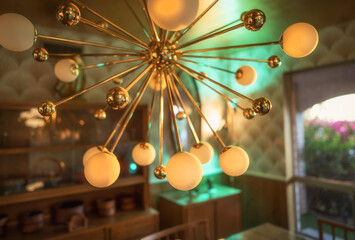 Close-up of a large gold Sputnik chandelier in a mid-century dining room. The dramatic fixture...